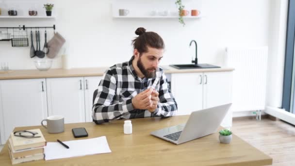 Taşınabilir Bilgisayar Ilaçlarla Masada Otururken Kareli Gömlekli Sağlıksız Bir Erkek — Stok video