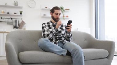 İşveren için kapalı alanda proje yaparken meslektaşına mesaj atan verimli bir serbest çalışan. Evde modern işyerinde kalırken elinde akıllı telefon tutan kareli gömlekli beyaz bir erkek..