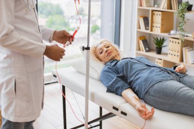 Verimli pratisyen hekim muayene koltuğunda yatan dişinin kan akışını kontrol ediyor. Genç bir erkek sistem incelemesi yaparken, beyaz yaşlı bir kadının kan nakli yaptığı görüntüler..