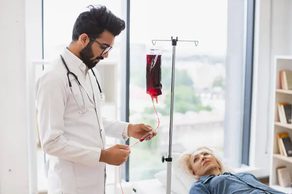 Eine Ältere Frau Die Bluttransfusionen Durchführt Schaut Einen Arzt Laborkittel lizenzfreie Stockbilder