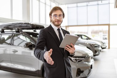 Başarılı sakallı menajer, yeni araba galerisi geçişlerinin arka planında alıcıyla el sıkışıyor. Kendine güvenen beyaz adam, takım elbiseli satıcı ve kravatlı parlak modern araba servisinde duruyor..