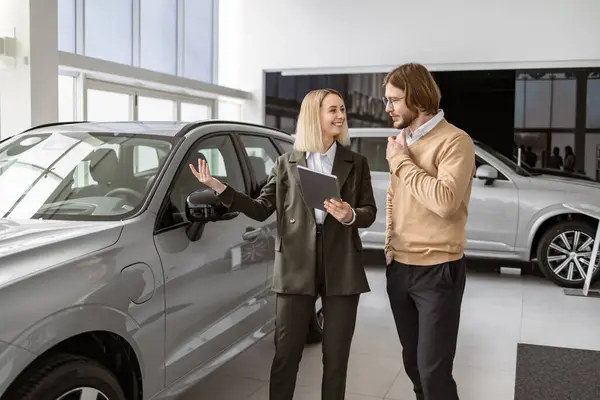 Confident Blond Saleswoman Explaining All Car Features Using Tablet Handsome Royalty Free Stock Photos
