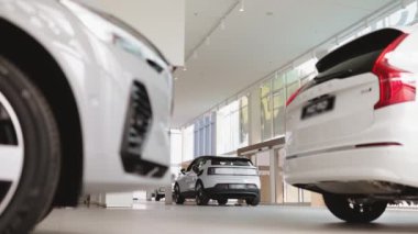 Yeni marka elektrikli SUV 'nin dışı. Işık bayiinde. Modern sergi salonundaki panoramik pencereli beyaz elektrikli arabada şarj aleti..