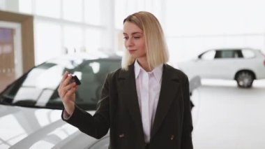 Gülümseyen satıcı, galerideki yeni arabanın anahtarını müşteriye veriyor. Araba satıcısı neşeyle gülümsüyor, elinde anahtarlar, satılık yeni araçların önünde duruyor. Teklif, indirim kavramı