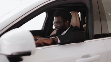 Sakin Afrikalı bir adam, müşteri, müşteri, takım elbiseli bir müşteri direksiyonda el ele tutuşan bir müşteri araba galerisinde araba galerisinde araba galerisi galerisinde araba galerisinde yeni bir araba almak isteyen birini seçin. Satış konsepti.