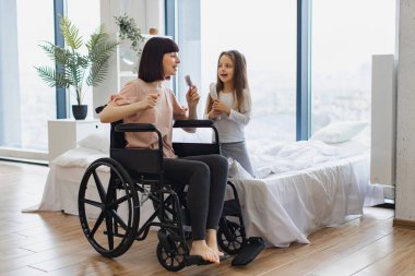 Özürlü anne, yatak odasında otururken mikrofon yerine taraklar kullanarak sevimli küçük kızıyla şarkı söylüyor. Mutlu bir aile hafta sonu sabahı eğleniyor..