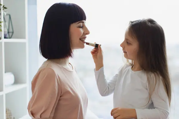 Die Tochter Malt Ihrer Schönen Mama Lippen Kleines Mädchen Schminkt lizenzfreie Stockbilder