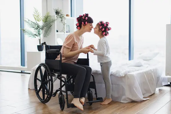 Junge Mutter Rollstuhl Hält Ihre Kleine Tochter Wochenendmorgen Schlafzimmer Glücklich lizenzfreie Stockbilder