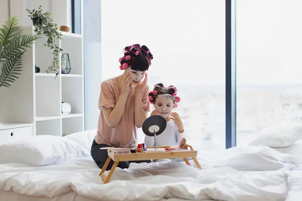 Young Woman Small Child Sits Bed Looking Mirror Applying Moisturizing kuvapankkikuva