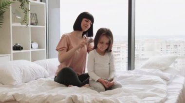 Yong Anne, günlük kıyafetleriyle küçük kızının saçını fırçalıyor yatak odasındaki büyük panoramik pencerenin yanında oturuyor. Mutlu Kafkas ailesi hafta sonu sabahları eğleniyor..