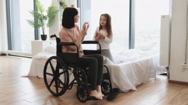 Özürlü anne, yatak odasında otururken mikrofon yerine taraklar kullanarak sevimli küçük kızıyla şarkı söylüyor. Mutlu bir aile hafta sonu sabahı eğleniyor..