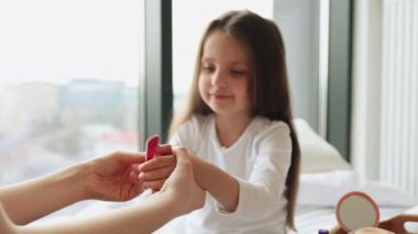 Annem manikür yapmadan önce güzel kızlarının tırnaklarını temizlemek için bir dosya kullanıyor. Küçük kızların ellerinin yakın plan görüntüsü.