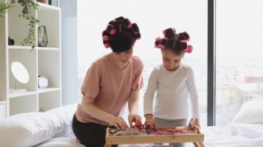 Kafkas ailesi anne ve kızı hafta sonları yatakta otururken kozmetik işlemler yapıyorlar. Genç bir kadın ve güzel bir kız kozmetik masasından göz bandı alıyor..