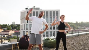 Beyaz tişörtlü pozitif adam ve siyah bluzlu kadın kollarını kaldırarak spor yapıyorlar. Mutlu spor çifti sabah sağlık jimnastiğine katılıyor..