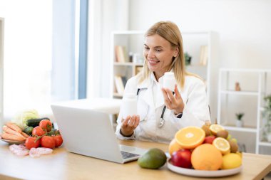 Olgun beslenme uzmanı kadın doktor bilgisayarı kullanarak hastaya tıbbi tedaviyi bir video konferansında açıklıyor. Teletıp ve teletıp kavramı.