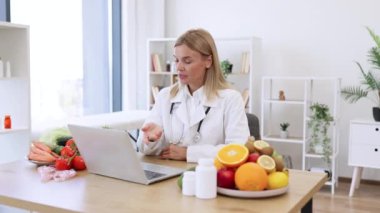 Dost canlısı, olgun bir kadın hastanedeki doktorların iş yerindeki kablosuz cihazla video görüşmesi yapıyor. Müşterilerin gıdaları tanımlamada ilerleme kaydetmeleri hakkında çevrimiçi danışmanlık sunan dikkatli dietisyen.
