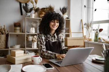 E-ticaret girişimciliği mi? Kadın çevrimiçi bir mağaza bir depoya nakliye siparişi hazırlıyor. Küçük işletme sahibi el yapımı ürünlerini karton kutuya koyuyor..
