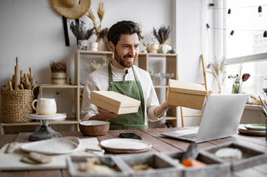 Erkek çevrimiçi mağaza bir depoya nakliye siparişi hazırlıyor. E-ticaret girişimciliği mi? Küçük işletme sahibi el yapımı ürünlerini karton kutuya koyuyor..