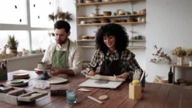 Sakallı adam önlük kasesinde, kadın ise çömlek atölyesinde merdaneyle kil yuvarlarken. Yaratıcı takım çalışması kavramı.