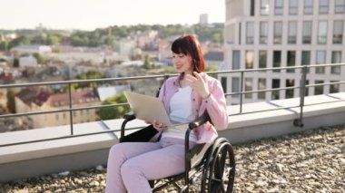 Tekerlekli sandalyedeki genç ve güzel kadın iş görüşmesi sırasında görüntülü konuşma yapıyor. Çevrimiçi uzaktan kumanda ve engellilik kavramı.