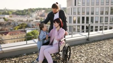 Baba ve kızı, boş zamanlarını temiz havada geçirirken anneyi ciddi yaralanma tedavisinde destekliyor. Tekerlekli sandalyedeki genç kadın modern evin terasında ailesiyle eğleniyor..