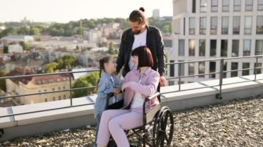 Baba ve kızı, boş zamanlarını temiz havada geçirirken anneyi ciddi yaralanma tedavisinde destekliyor. Tekerlekli sandalyedeki genç kadın modern evin terasında ailesiyle eğleniyor..