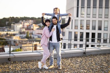 Üç kişilik sevimli bir aile çatıda kaliteli zaman geçiriyor. Anne, baba ve kız dışarıda neşeli anlar paylaşıyorlar..