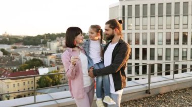 Mutlu aile şehir merkezindeki terasta yeni ev anahtarını kutluyor. Çocuklu gülümseyen ebeveynler önemli bir olayın tadını çıkarıyorlar..