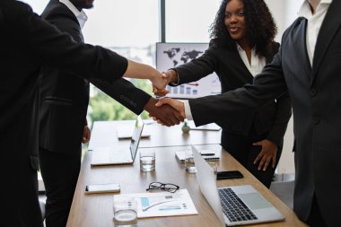 Resmi giyinmiş iş adamları konferans masasında el sıkışıyorlar. Başarılı bir anlaşmayı ya da modern ofis ortamını simgeliyorlar..