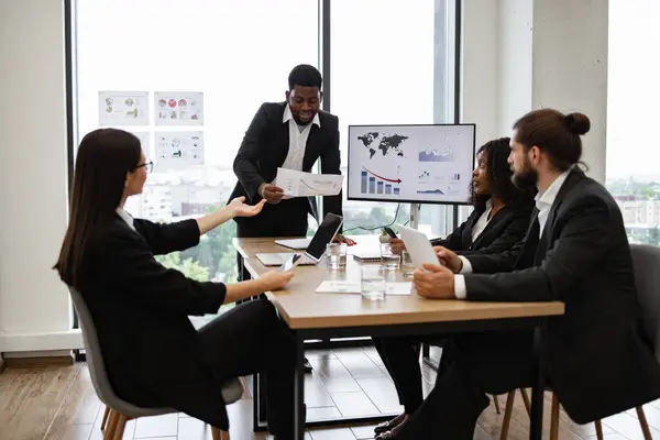 stock image Business team in a meeting analyzing data, charts, and graphs. Professionals in formal attire discussing business plans and strategies in a modern office setting.