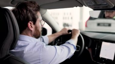 Araba alışverişi, satın alma ve bayilik kavramı. Modern bir arabanın içinde, elinde direksiyon tutarken gülümseyen bir iş adamı. Adam mutlu görünüyor, test sürüşüne ya da araç almaya hazır..