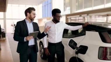 Satıcı ve işadamı modern araba galerisinde elektrikli cipi tartıştılar. Çevre dostu ulaşım odaklı iş ortamı. Konuşma ve karar verme süreci.