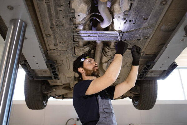 Mechanic Using Tools While Working Car Hydraulic Lift Garage Focused Royalty Free Stock Images