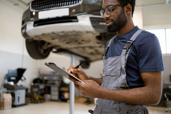 Mechanic Carefully Inspecting Car Auto Repair Shop Clipboard Focused Professional Stock Photo