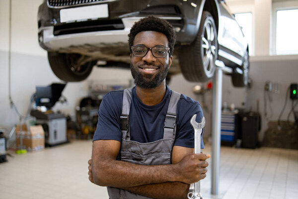 Auto Mechanic Standing Garage Holding Wrench Car Lifted Smiling Technician Stock Photo