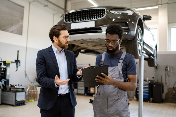 Automotive Manager Talking Mechanic Vehicle Repairs Using Tablet Workshop Professionals Royalty Free Stock Images