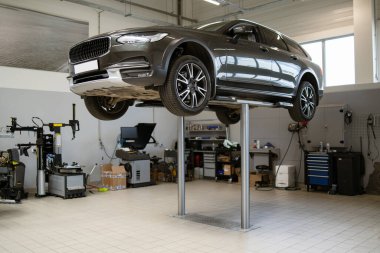 Araba modern oto tamirhanesinde hidrolik asansörle yükseltilmiş. İyi donanımlı, temiz bir garaj, çeşitli aletler ve makinelerle görülebilir. Araç bakımı, onarım ve hizmet kavramı.