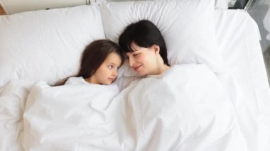 Anne ve kızı beyaz çarşafların altında yatıyorlar. Aile bağı, huzurlu ve rahat bir an. Ebeveyn-çocuk ilişkilerinde sevgi, sıcaklık ve güvenlik kavramını yakalamak.