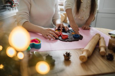 Kafkas anne ve kızı hamur üzerinde kurabiye keskisi kullanarak birlikte yemek pişiriyorlar. Bayram yemeği pişirmek neşe ve beraberlik getirir..