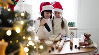 Neşeli Kafkas anne ve kızı Noel tatili boyunca mutfakta birlikte yemek pişiriyorlar. Tatil süslemeleriyle çevrili kasedeki malzemeleri karıştırıyorum..