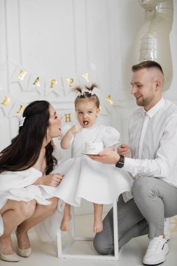 Kafkas ailesiyle doğum günün kutlu olsun. Genç ebeveynler ve küçük kız birlikte pastanın tadını çıkarıyorlar. Baba küçük pastayı tutarken anne sevgiyle kızına bakıyor..