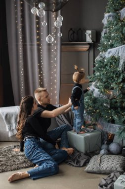 Kafkas ailesi, evde birlikte Noel ağacı süsleyen genç anne, baba ve çocuğu da içeriyor. Manzara, tatil sezonunun sıcaklığını ve neşesini samimi bir şekilde yakalar..