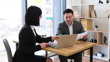 Gri takım elbiseli Asyalı işadamı, Kafkasyalı iş kadınıyla modern bir ofiste görüştüğünü bildirdi. Takım çalışmalarının ve kurumsal çevrenin önemini vurgulayarak ciddi bir tartışmaya giriştiler..