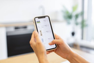 Beyaz bir kadın akıllı telefondan kozmetik ürünlerine göz atıyor. Resim dijital alışveriş deneyimini yakalar, evden güzellik ürünleri satın almanın kolaylığını vurgular.