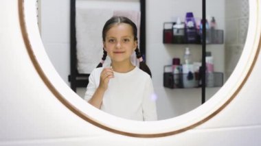Düşen dişi tutan, gülümseyen ve banyoda baş parmağını sallayan beyaz bir kızın portresi. Neşe ve çocukluk deneyimlerini yansıtır..
