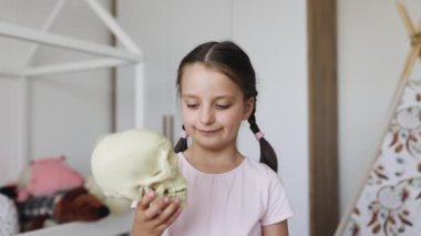 Kafkasyalı küçük bir kızın portresi. Bebek dişleri kayıp. Elinde insan kafatası modeli var..