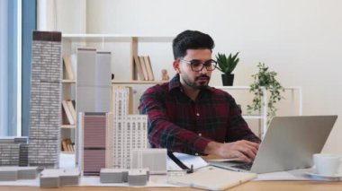 Genç Hintli erkek mimar ofiste detaylı şehir modeli planı üzerinde çalışıyor. Profesyonel çalışma ortamında mimari, tasarım ve yaratıcılık kavramı.