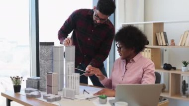 Hintli erkek ve Afrikalı kadın mimarlar modern şehir için model projesinde işbirliği yaparlar. Yaratıcı tartışma ve kentsel planlama ile parlak ofis ortamında çeşitli takım çalışmaları.