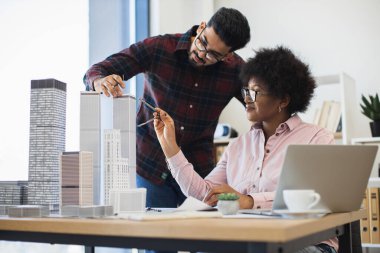 Hintli erkek ve Afrikalı kadın mimarlar modern şehir için model projesinde işbirliği yaparlar. Yaratıcı tartışma ve kentsel planlama ile parlak ofis ortamında çeşitli takım çalışmaları.