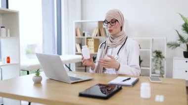 Müslüman kadın doktor internetten hastaya danışmanlık yapıyor. Video aracılığıyla ilaç tedavisi uyguluyor. Uzman sağlık çalışanı uzaktan tıbbi danışmanlık için teknolojiyi kullanıyor..